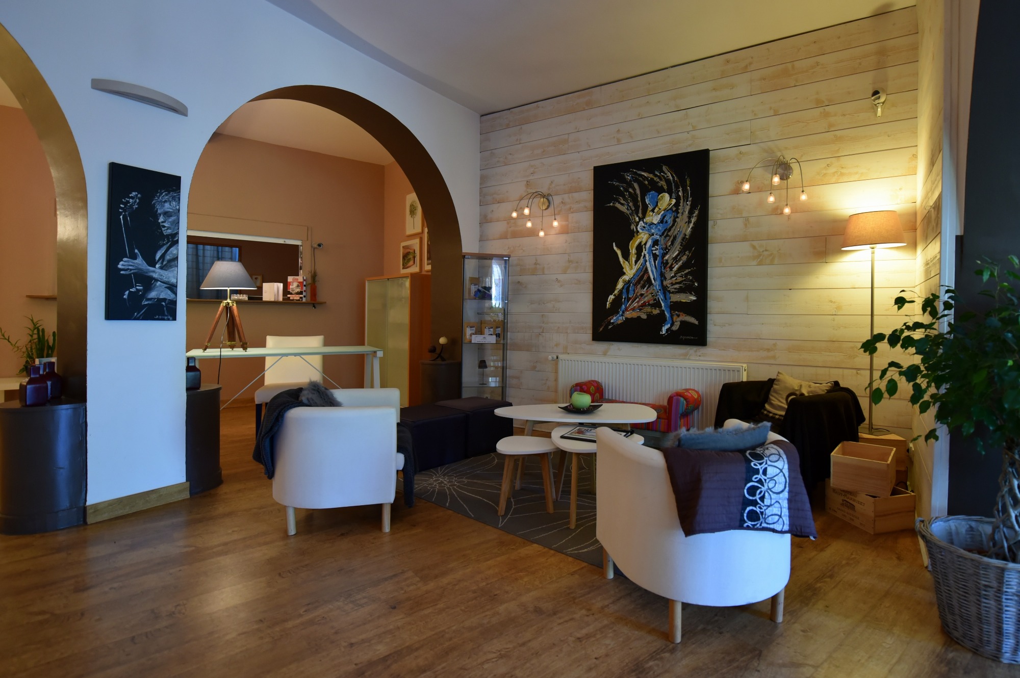 Trois fauteuils confortables vous invitent à un moment de détente, éclairés par deux appliques murales et une lampe sur pied