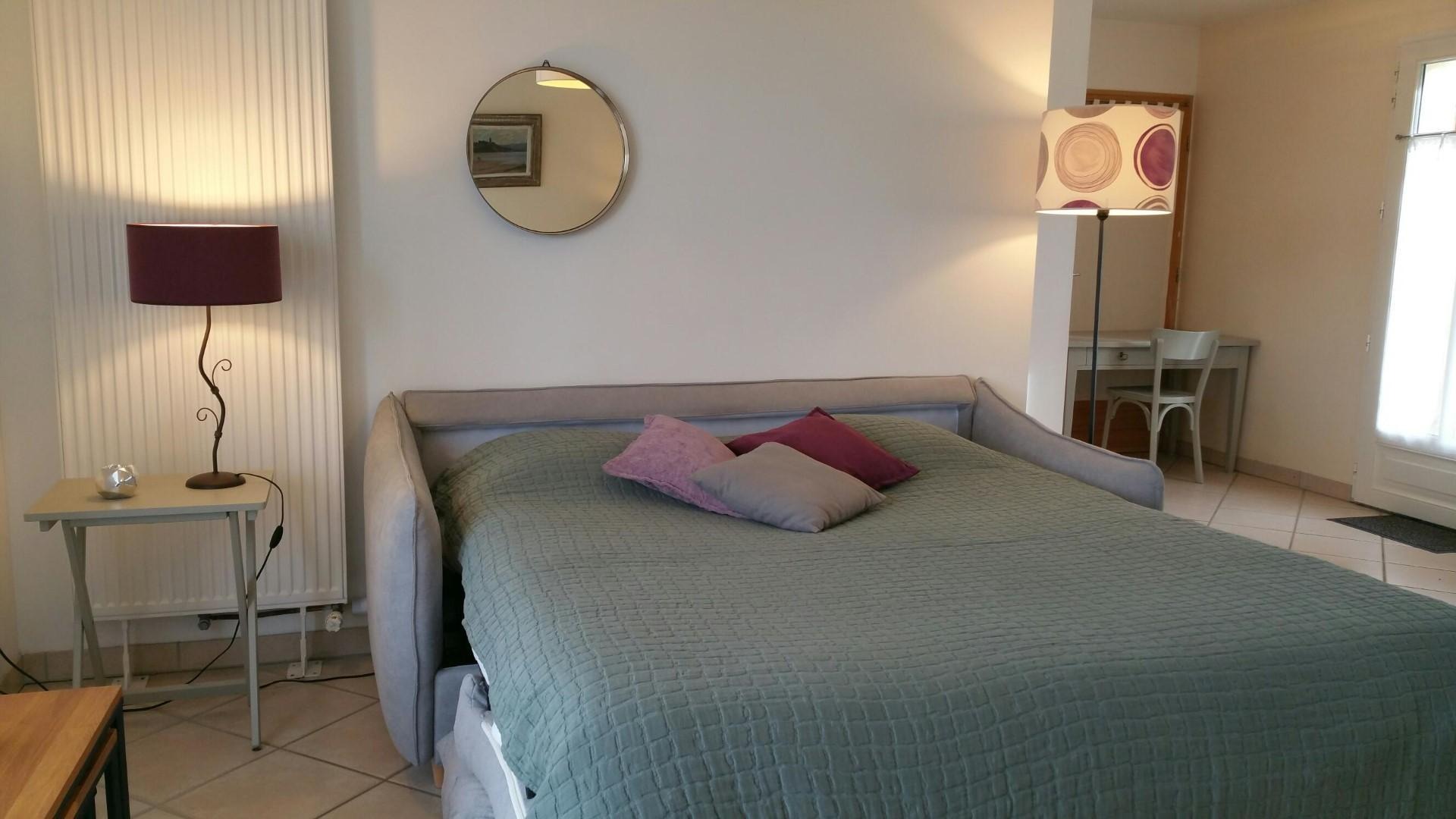 Canapé-lit ouvert avec au fond une table et une chaise