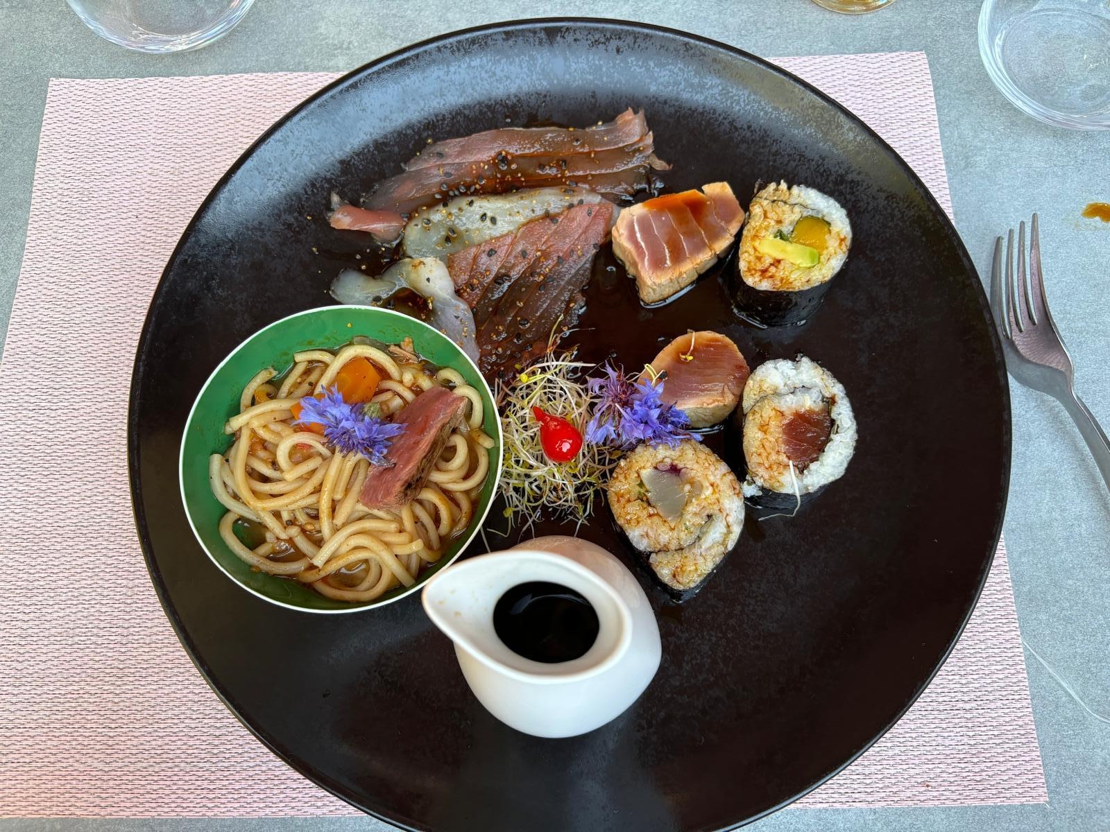 Assortiment d'inspiration asiatique associant thon mariné, makis, nouilles sautées.