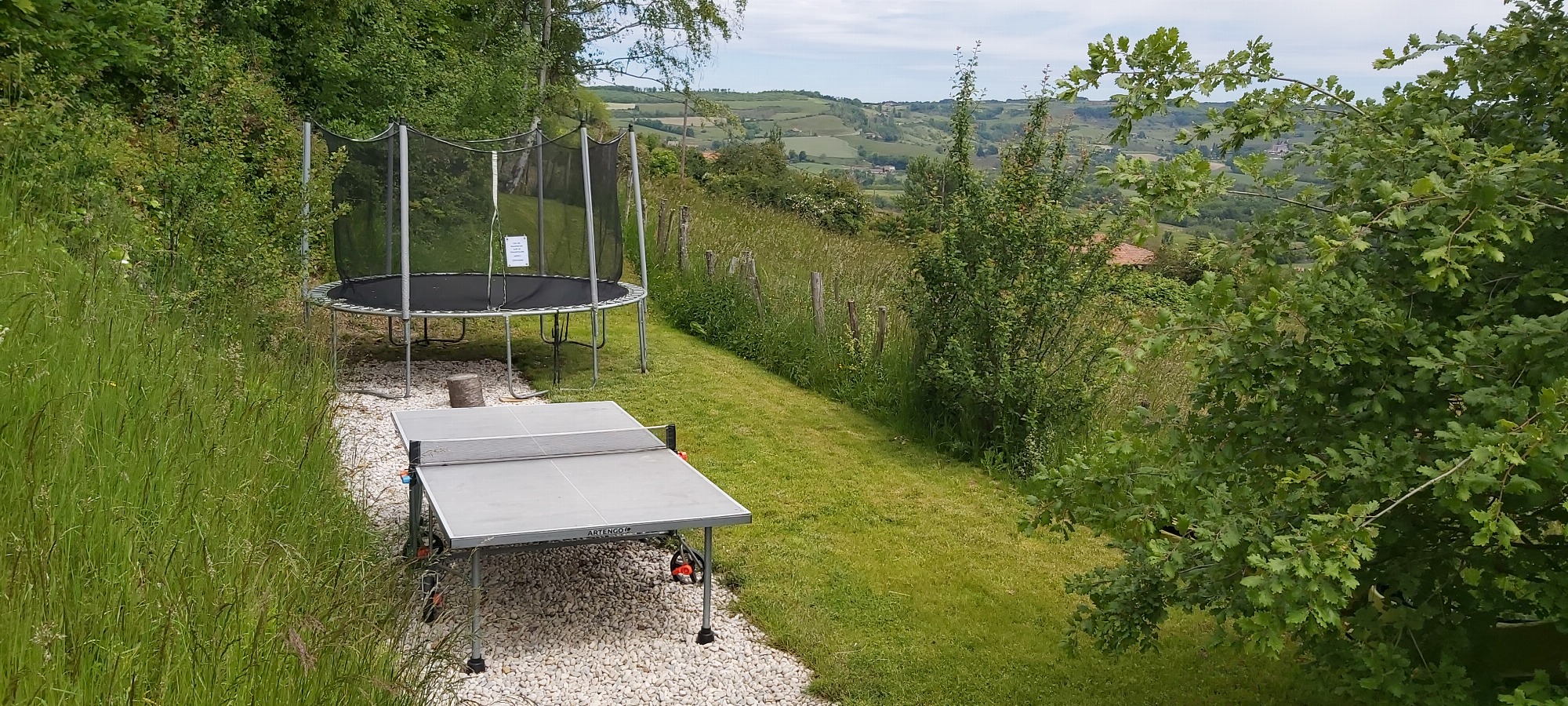 Coin jeux avec trampoline géant pour les enfants et table de ping-pong.