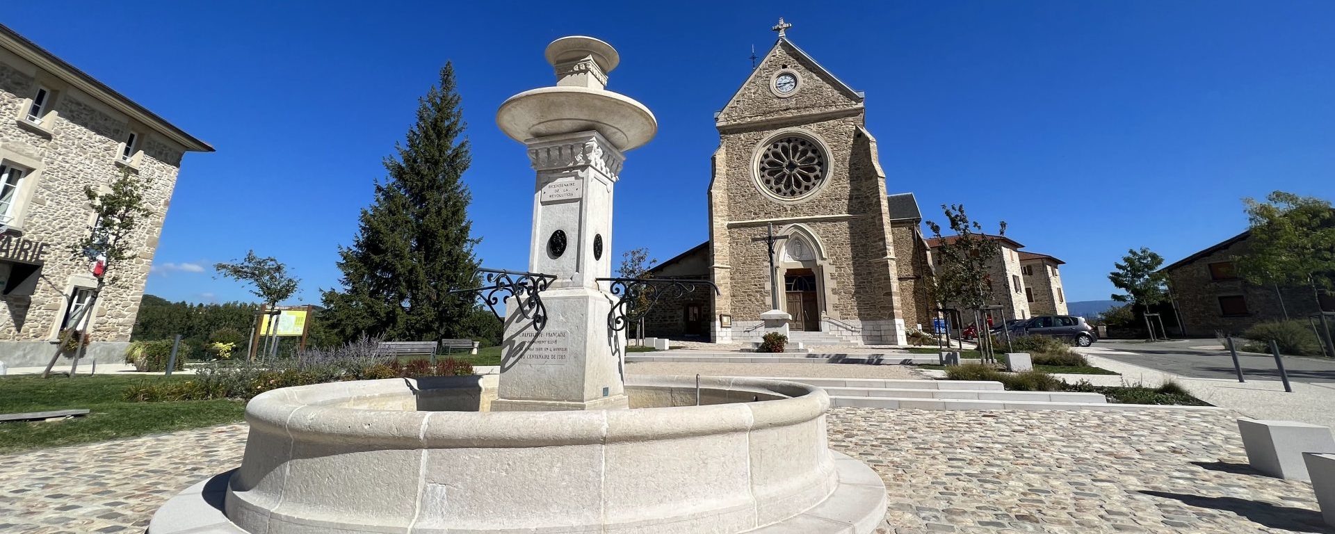 place du village de Varacieux en Isère avec la fontaine au centre et l'église
