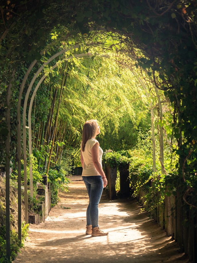 femme sous des haies végétales au jardin des fontaines pétrifiantes