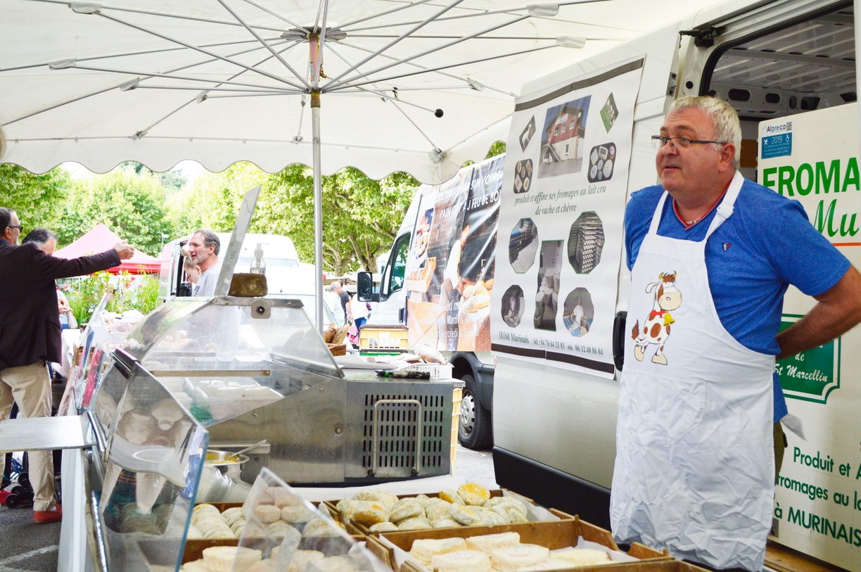 exposant en train de vendre du fromage de saint-marcellin sur le marché
