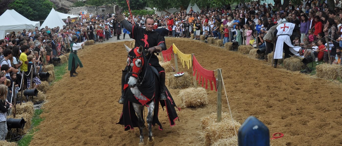 Joute équestre de La Médiévale à Saint-Antoine-l'Abbaye : chevalier sur son cheval caparaçonné devant une foule de spectateurs en Isère