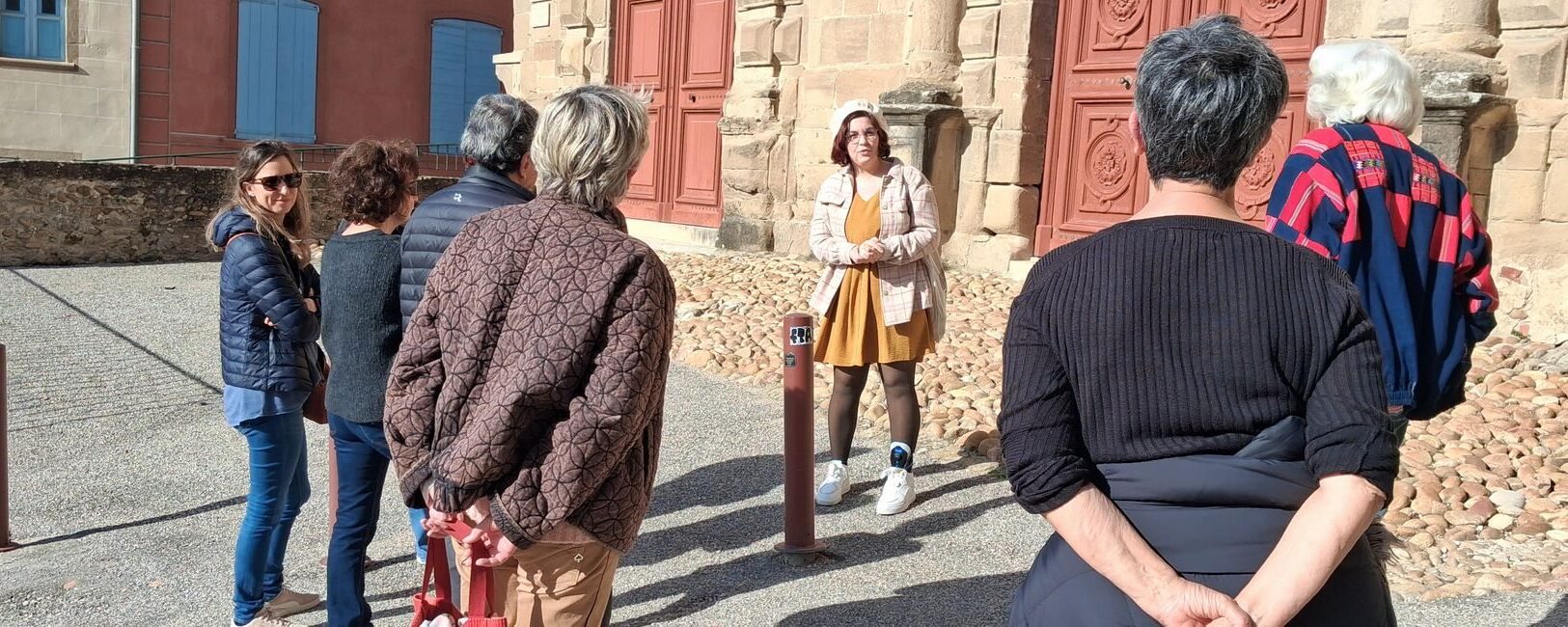 Groupe en visite guidée devant l'église abbatiale de Saint-Antoine-l'Abbaye, Isère